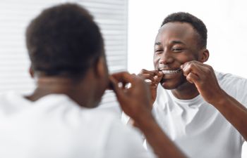 Afro-american man flossing his teeth.