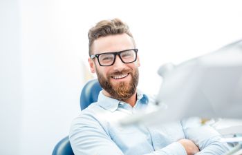 Satisfied man with a perfect smile sitting in a dental chair.