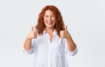 Happy middle-aged woman with a perfect smile showing her thumbs up.