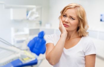 Upset woman with dental problem at dentist's office.