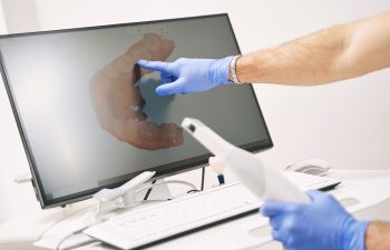 A dentist pointing at a digital dental imaging.